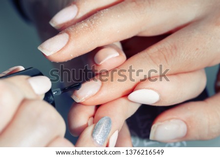 The hands of the master of the hardware manicure and the hands of the client close-up during the application of varn