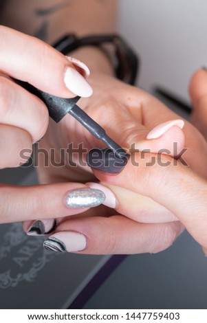 The hands of the master of the hardware manicure and the hands of the client close-up during the application of varn