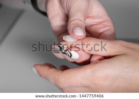 The hands of the master of the hardware manicure and the hands of the client close-up during the application of varn