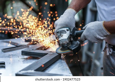 the hands of the master saw the metal with a grinder. metal works in the workshop close up - Powered by Shutterstock