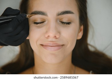 hands of the master who performs the procedure of permanent makeup of eyebrows view from above. Permanent eyebrow makeup PMU for brunettes.