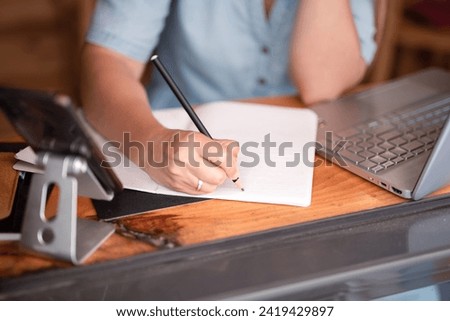 hands masterfully navigate laptop and smartphone, creating on a digital canvas. Nearby notebook harmonizes the blend of digital and analog tools, showcasing the modern professional's efficient and sti