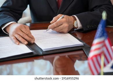 Hands of mature American delegate in formalwear signing contract of business partnership and pointing at signature while sitting by table - Powered by Shutterstock