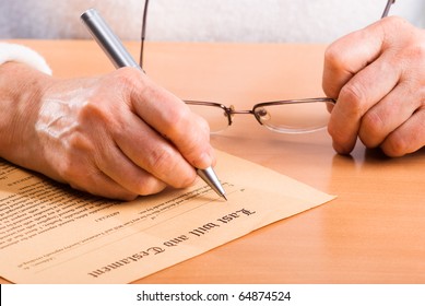 Hands of mature woman signature Last Will sitting on desk
