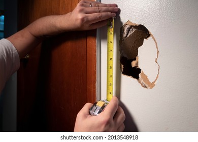 Hands Measure Hole In Damaged Drywall