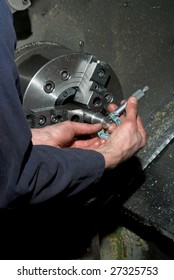 Hands measuring diameter of machined piece using a tool on a CNC lathe