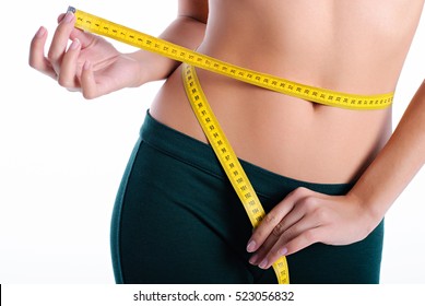 hands measuring waist with a tape. Fit and healthy woman on white background