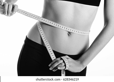 hands measuring waist with a tape. Fit and healthy woman on white background. Black and whie
