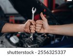 Hands of mechanic and client, holding tool, car service station.