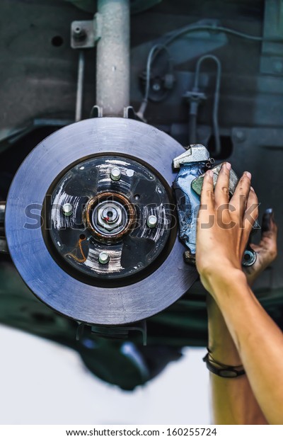 Hands of a mechanic install brake lining onto a car\
disc brake