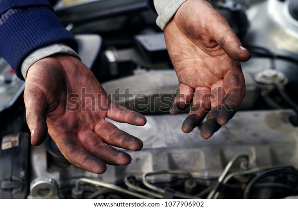 Hands of a mechanic in oil and fuel oil with a\
wrench during repair of the\
engine