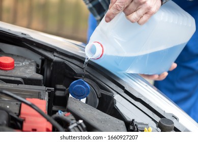 Hands Of Mechanic Pouring Blue Windshield Washer Fluid In A Car