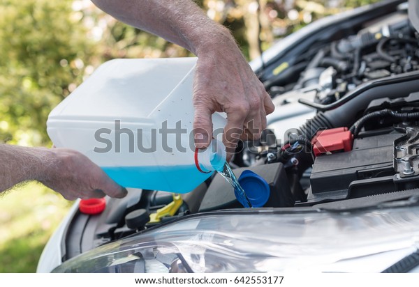 Hands of\
mechanic pouring windscreen washer in a\
car