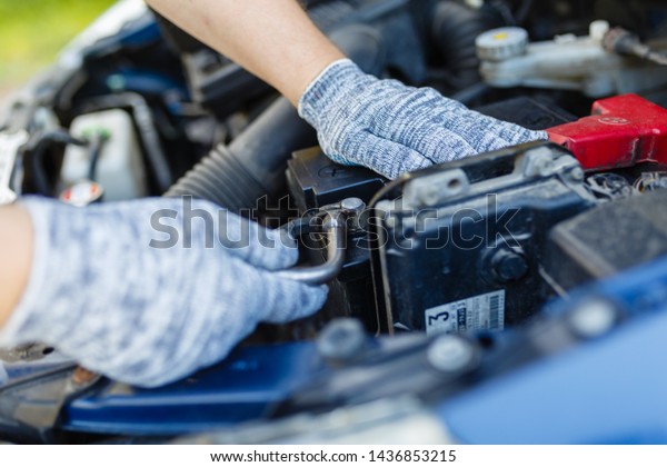 Hands of mechanic repairing\
the engine of the special keys (wrenches and ratchets).\
Professional car mechanic in gloves working on the side of the\
road, field service.