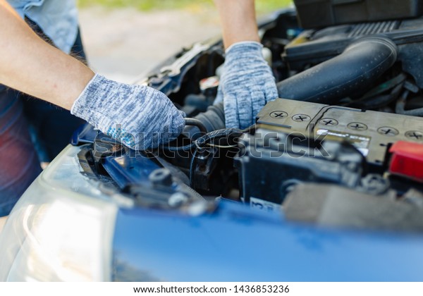 Hands of mechanic repairing\
the engine of the special keys (wrenches and ratchets).\
Professional car mechanic in gloves working on the side of the\
road, field service.
