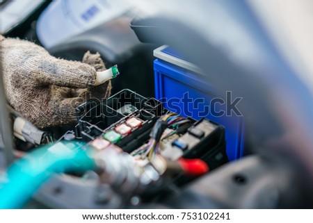 The hands of the mechanic replacing  fuse in car and selects the correct fuse at garage .service and maintenance concept . selective focus
