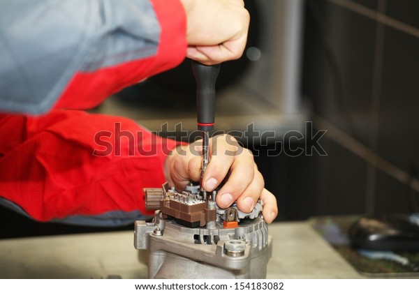 Hands of mechanic\
restores a generator