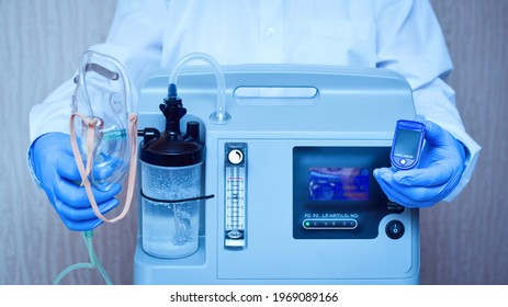 Hands in medical gloves hold an oxygen mask from the generator oxygen concentrator, which helps with low lung oxygen saturation, with pneumonia Covid-19 and pulse Oximeter in the other hand