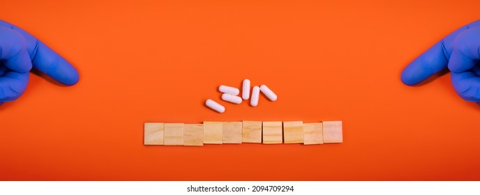 Hands in medical gloves point on wooden blocks on colored orange background with medicine pills. Concept book cover medical scientific or biological template. Advertising mock up. Calendar flat lay