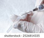 Hands in medical gloves remove cap from syringe needle. Opening syringe. Routine vaccinations for children concept. Vaccination. Sterile medical items. Open syringe needle for injection. Antibiotics.