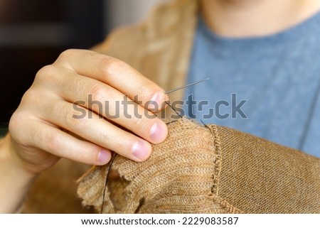 Hands men close-up. Mending clothes, sewing and darning, and fashionable needlework. Selective focus