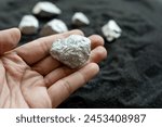 The hands of men are holding at the silver or platinum or rare earth minerals ore in their hands from the mine