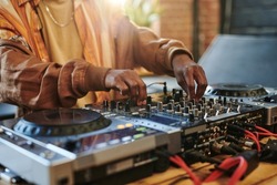 Hands Of Modern Black Man Regulating Sounds On Dj Set While Standing By Table In Studio Or Loft Apartment And Turning Mixers