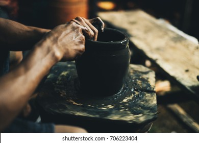 Potter’s hands molding a black clay pot on a makeshift. Side view. Selective focus. - Powered by Shutterstock