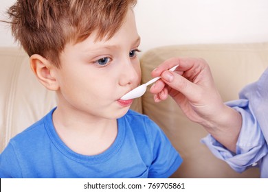 Hands Of Mom Giving Cough Syrup Medicine On Spoon To Sick Son