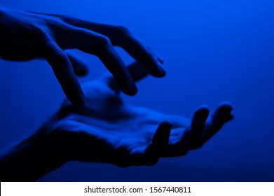 Hands In Monochrome Blue Contrast Neon Light. Man Showing Hand Palm Gesture Sign. Artistic Photography.