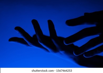 Hands In Monochrome Blue Contrast Neon Light. Man Showing Hand Palm Gesture Sign. Artistic Photography.