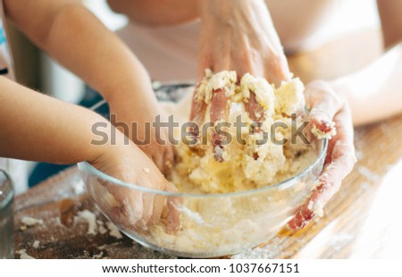 Hands of mother and child in a bowl making dough