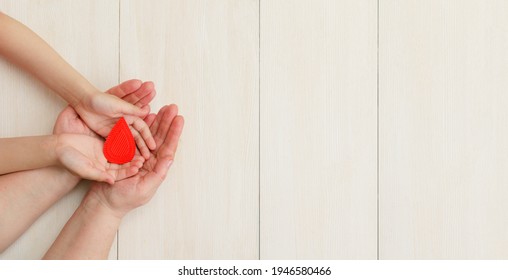 Hands Of The Mother And Child Hold Drop Of Blood On A White Background.Concept Of Give Blood Donation, Blood Transfusion, World Hemophilia Day.World Health Day. Layout.Copy Space.banner