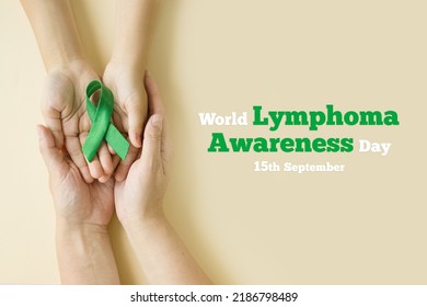 Hands of mother and child hold green ribbon - symbol of fight against disease. World lymphoma awareness day. September 15. Liver, Gallbladders bile duct, kidney Cancer and Lymphoma Awareness month - Shutterstock ID 2186798489