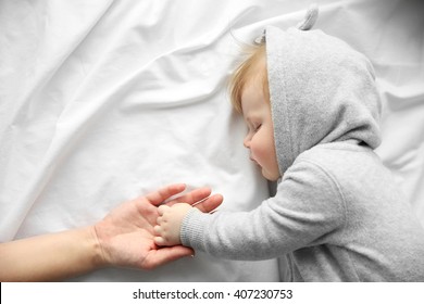Hands of mother and her little baby boy on the bed, close up - Shutterstock ID 407230753