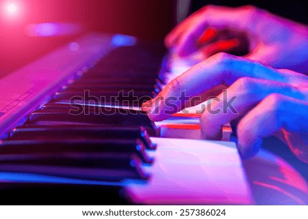 hands of musician playing keyboard in concert with shallow depth of field