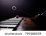The hands of a musician playing the marimba in dark tones 