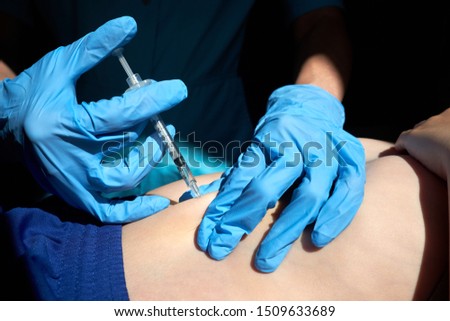 Hands of nurse in blue surgical gloves making injection of anticoagulant subcutaneously to child. Closeup view.