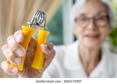 Hands Of Old Elderly Patient Is Doing Palm Or Wrist Exercise With Spring Hand Grip,squeeze With Hand Expander,stretch The Fingers Tendon,treat Muscle Weakness,Parkinson's Disease,health Care Concept