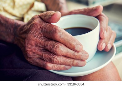 Hands Of Old Man Holding Cup Of Coffee.