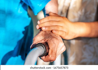 Hands of an old man on a walker. Care for the elderly. Coronovirus takes old people. Family care for the old people. Generations Hands of an old man and a child