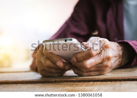 hands of old man working with digital smart phone , in wood table