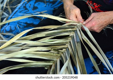 Hands of an old Maori woman weaving a traditional Polynesian woven artwork.
