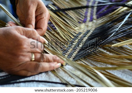 Hands of an old Polynesian Maori woman weaving a traditional woven artwork mat in Auckland, New Zealand.