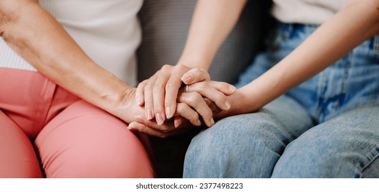 Hands of the old woman and a woman hand on the sofa  in liveing room - Shutterstock ID 2377498223