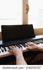 Hands Of An Old Woman Playing Piano In A House In Front Of A Window
