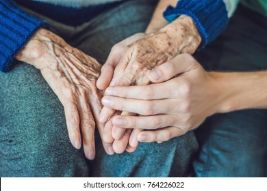 Hands of an old woman and a young man. Caring for the elderly. close up.