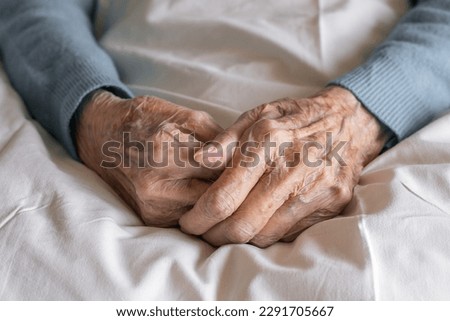 Hands of an old women close up on a bed in a hospital. Aging process, elderly women. High quality photo