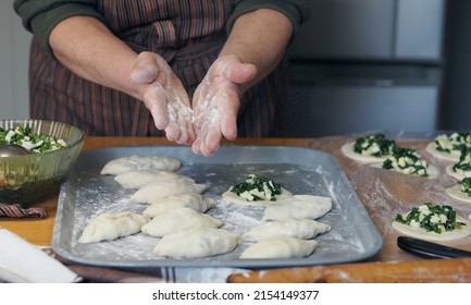 Hands Of An Older Woman In Flour. She Prepares Pies With Filling. Grandmother Cooks Pies In The Home Kitchen. Homemade Healthy Food. The Process Of Making Pies By Hand.