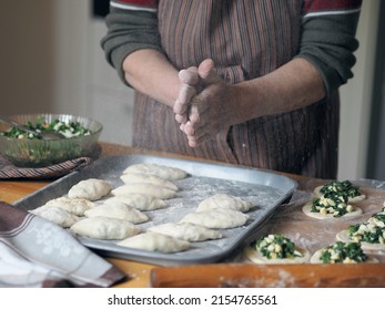 Hands Of An Older Woman In Flour. She Prepares Pies With Filling. Grandmother Cooks Pies In The Home Kitchen. Homemade Healthy Food. The Process Of Making Pies By Hand.